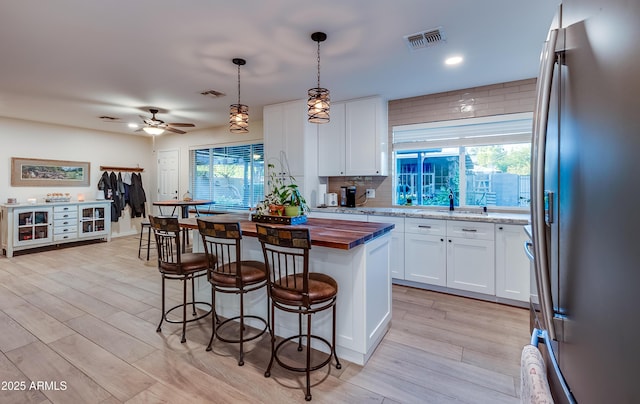 7226 E Virginia Ave, Scottsdale, AZ 85257 - kitchen featuring freestanding refrigerator, wood counters, a sink, a breakfast bar, and white cabinetry