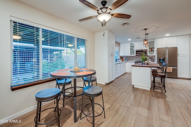 7226 E Virginia Ave, Scottsdale, AZ 85257 - kitchen featuring stainless steel appliances, a center island, white cabinets, glass insert cabinets, and a ceiling fan