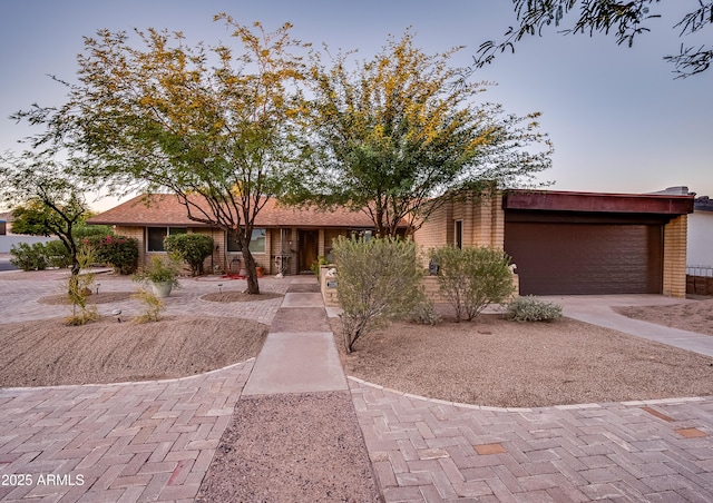 view of front of property featuring a garage, concrete driveway, and brick siding