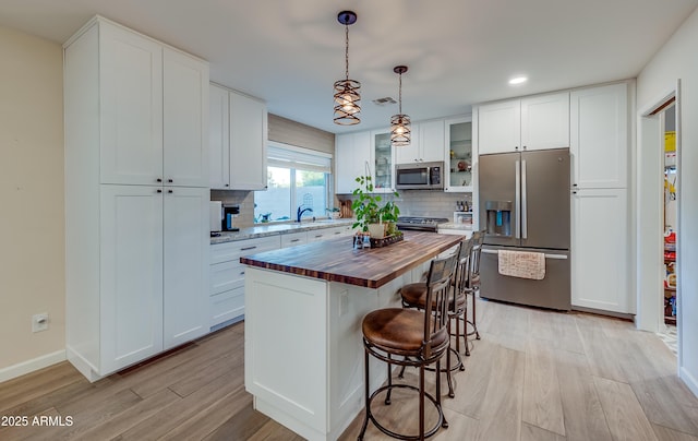 7226 E Virginia Ave, Scottsdale, AZ 85257 - kitchen with stainless steel appliances, butcher block counters, light wood-style flooring, a kitchen bar, and backsplash