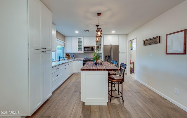 7226 E Virginia Ave, Scottsdale, AZ 85257 - kitchen featuring stainless steel appliances, butcher block counters, a breakfast bar, light wood-style floors, and backsplash