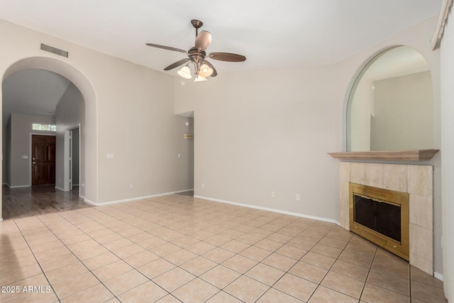 1915 E Golden Ct, Chandler, AZ 85225 - unfurnished living room with arched walkways, a tiled fireplace, visible vents, ceiling fan, and light tile patterned floors