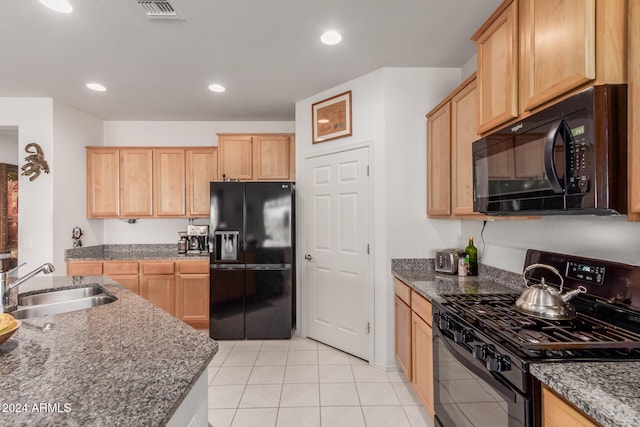 kitchen featuring dark stone counters, light brown cabinetry, sink, black appliances, and light tile patterned floors