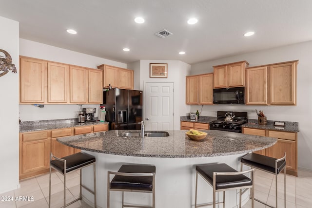 kitchen with an island with sink, a kitchen bar, sink, and black appliances