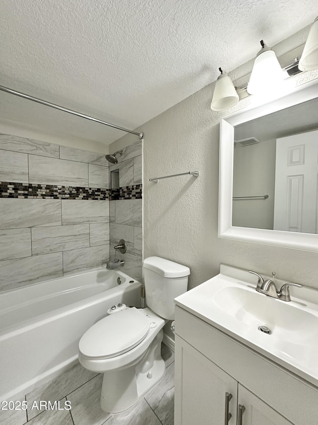 full bathroom featuring tiled shower / bath, vanity, toilet, and a textured ceiling