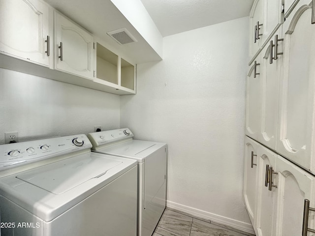 laundry room featuring washer and clothes dryer and cabinets