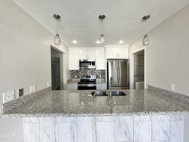 kitchen featuring stone counters, appliances with stainless steel finishes, white cabinetry, sink, and kitchen peninsula