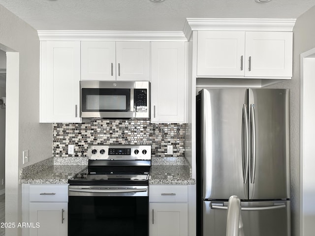 kitchen with light stone counters, appliances with stainless steel finishes, decorative backsplash, and white cabinets