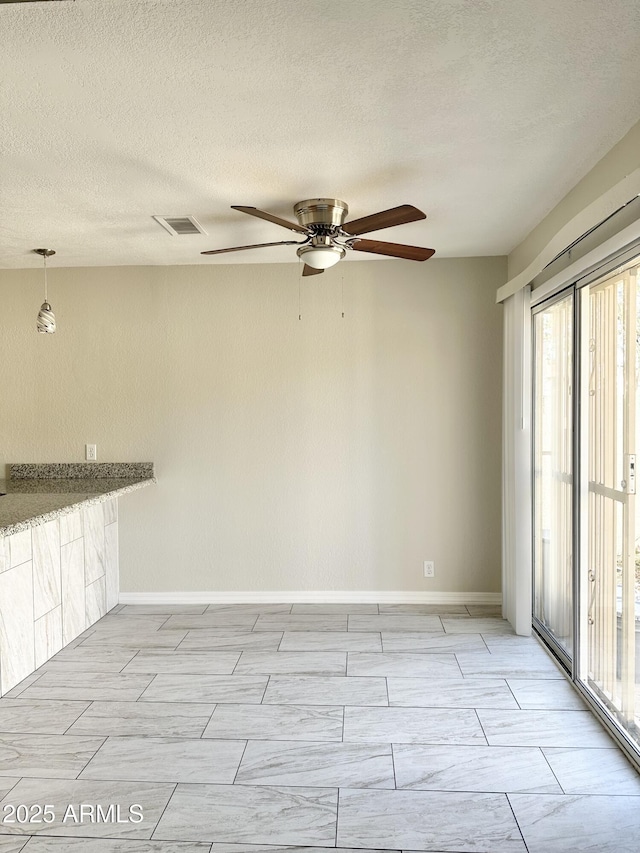 empty room featuring ceiling fan and a textured ceiling