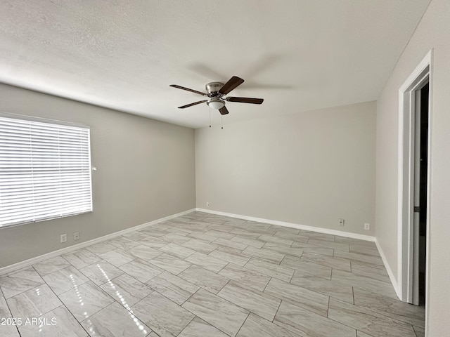 unfurnished room with ceiling fan and a textured ceiling