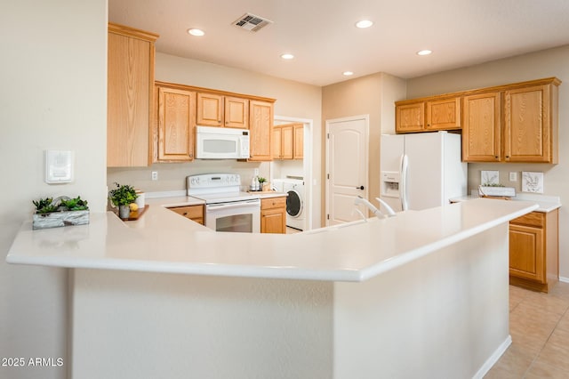 kitchen featuring light tile patterned flooring, washer / dryer, white appliances, and kitchen peninsula