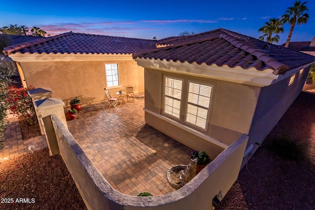 property exterior at dusk featuring a patio area