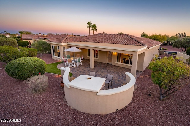 back house at dusk featuring a patio