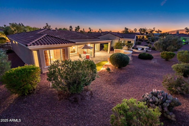 back house at dusk with a patio