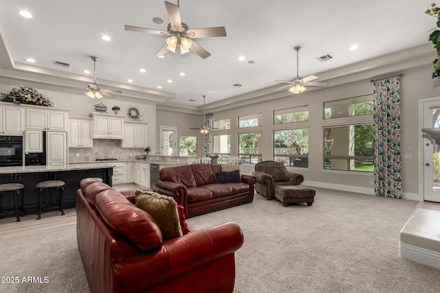 living room with plenty of natural light, visible vents, and light colored carpet