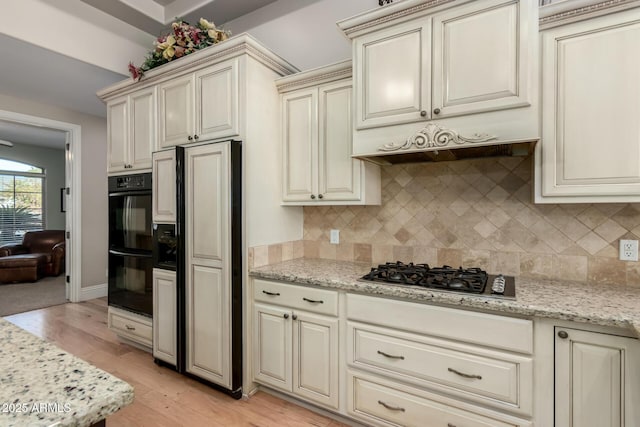 kitchen featuring dobule oven black, cream cabinetry, backsplash, light stone countertops, and stainless steel gas stovetop