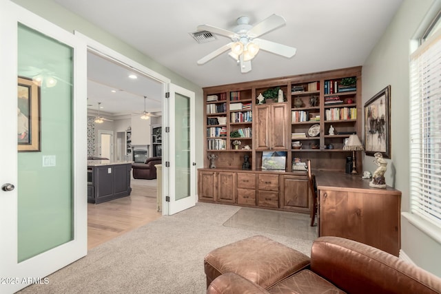 office space with visible vents, plenty of natural light, light carpet, and ceiling fan