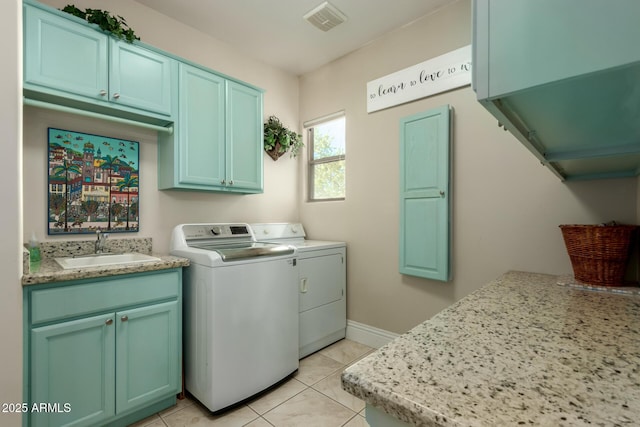 washroom with cabinet space, light tile patterned floors, visible vents, washing machine and dryer, and a sink