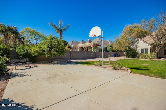 view of sport court with playground community, a yard, a fenced backyard, and community basketball court