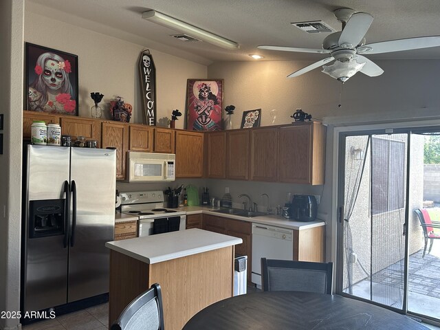 kitchen with a sink, a center island, white appliances, light countertops, and ceiling fan