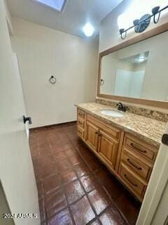 bathroom featuring tile patterned flooring, vanity, and a skylight