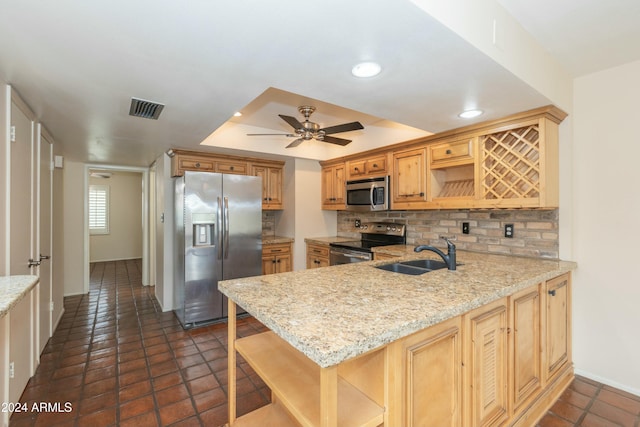 kitchen featuring appliances with stainless steel finishes, backsplash, ceiling fan, sink, and a breakfast bar area