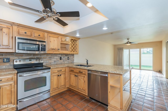 kitchen featuring ceiling fan, sink, kitchen peninsula, decorative backsplash, and appliances with stainless steel finishes