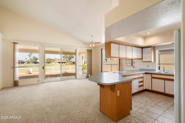 kitchen with light countertops, electric cooktop, light carpet, a sink, and a peninsula