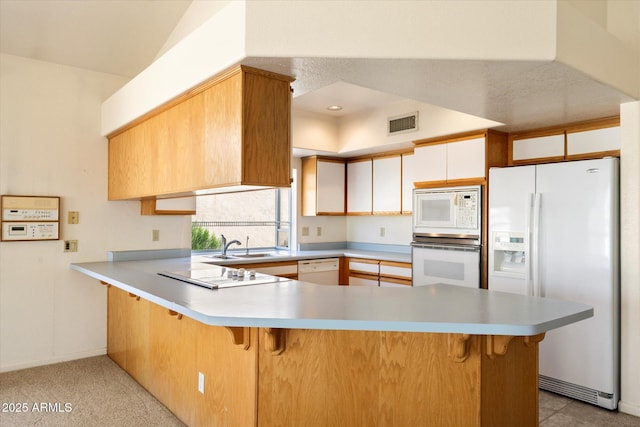 kitchen with visible vents, white appliances, light countertops, and a peninsula