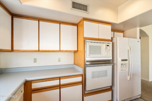 kitchen featuring carpet floors, light countertops, visible vents, white cabinets, and white appliances