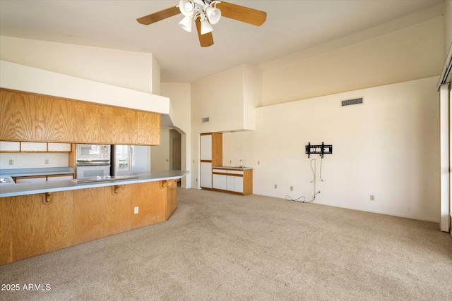 kitchen with arched walkways, a breakfast bar, light carpet, and visible vents