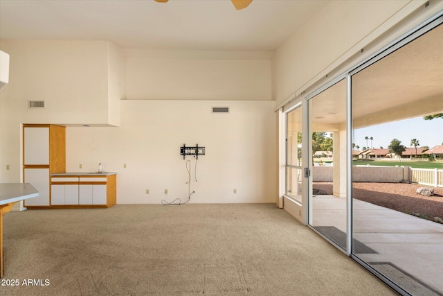 spare room with a high ceiling, carpet flooring, a sink, and visible vents