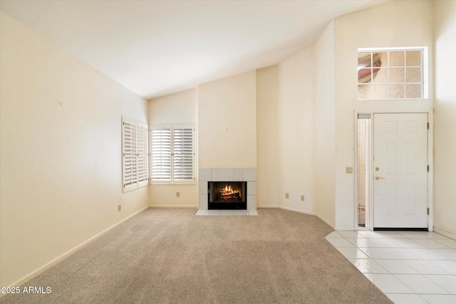 unfurnished living room featuring high vaulted ceiling, a tile fireplace, baseboards, tile patterned floors, and carpet