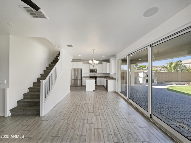 kitchen featuring a chandelier, stainless steel appliances, visible vents, a healthy amount of sunlight, and white cabinets