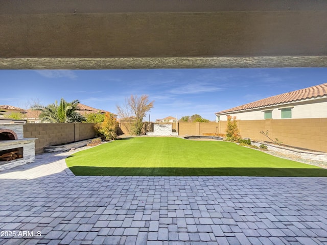 view of patio featuring an outdoor fireplace and a fenced backyard