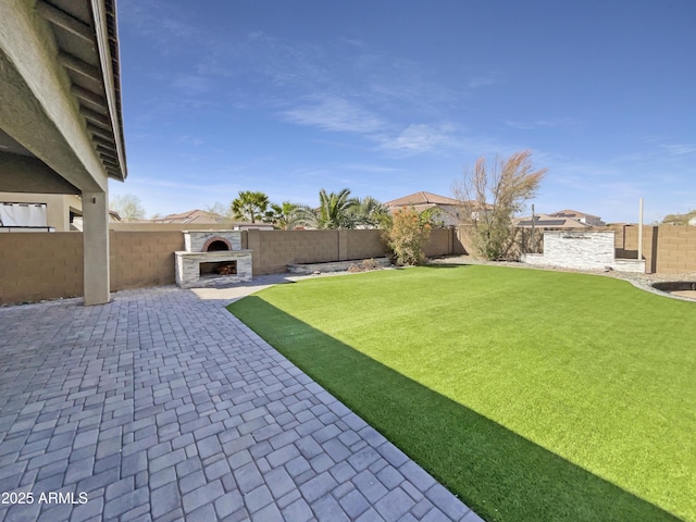 view of yard featuring a fenced backyard, an outdoor fireplace, and a patio