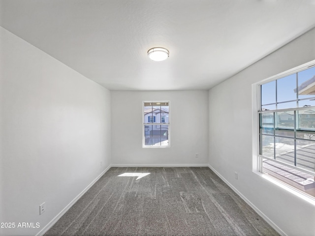 empty room with dark carpet and baseboards