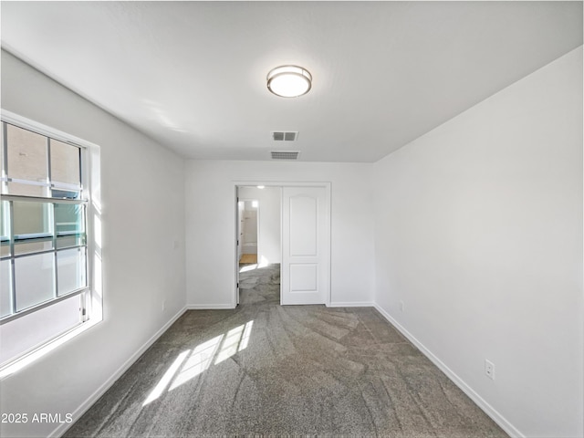 carpeted spare room with visible vents and baseboards