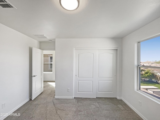 unfurnished bedroom with a closet, carpet flooring, visible vents, and baseboards