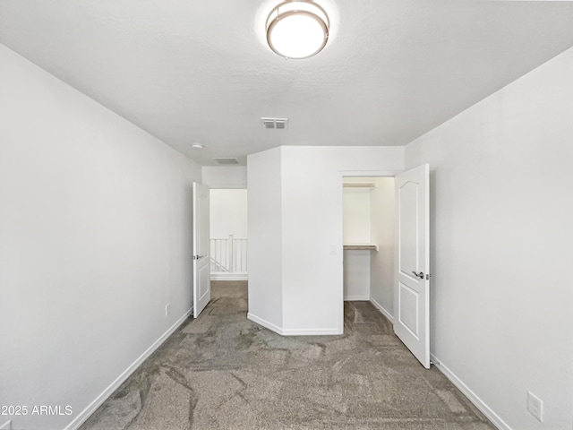 unfurnished bedroom with carpet flooring, visible vents, baseboards, a spacious closet, and a closet