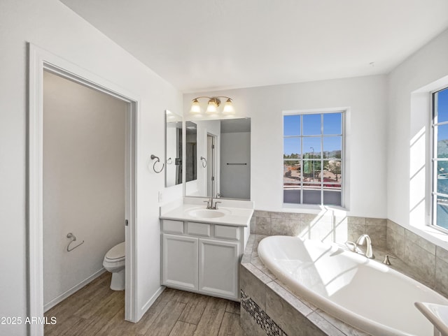 full bathroom with a garden tub, vanity, toilet, and wood finished floors