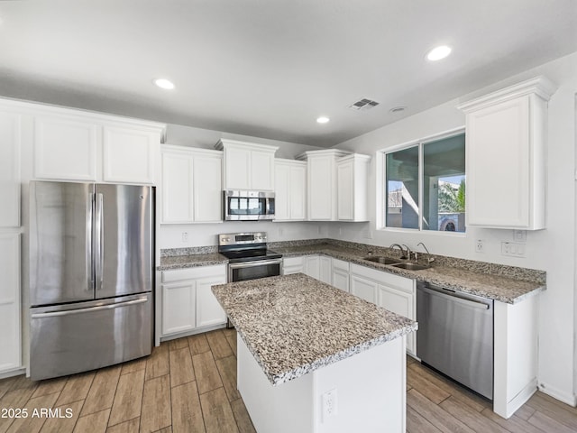 kitchen featuring stainless steel appliances, light wood-type flooring, white cabinets, and a sink