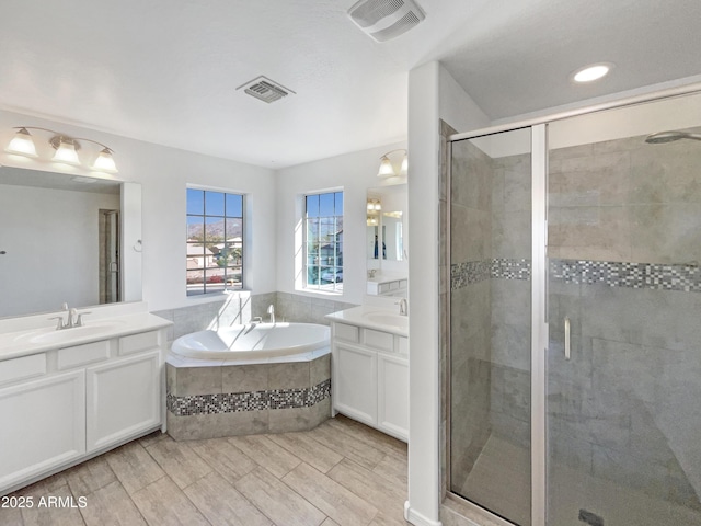 full bathroom with visible vents, a sink, a shower stall, and a garden tub