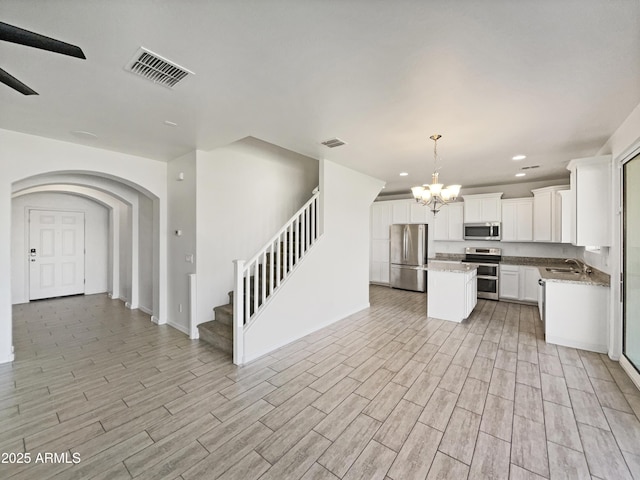 kitchen with appliances with stainless steel finishes, a kitchen island, visible vents, and light wood-style floors