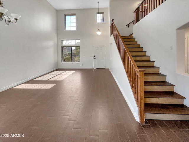 staircase featuring hardwood / wood-style floors, a towering ceiling, and a chandelier