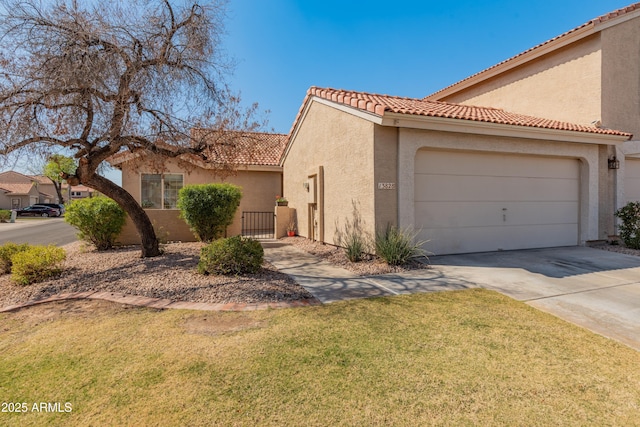 mediterranean / spanish house featuring a tile roof, concrete driveway, a front yard, stucco siding, and a garage