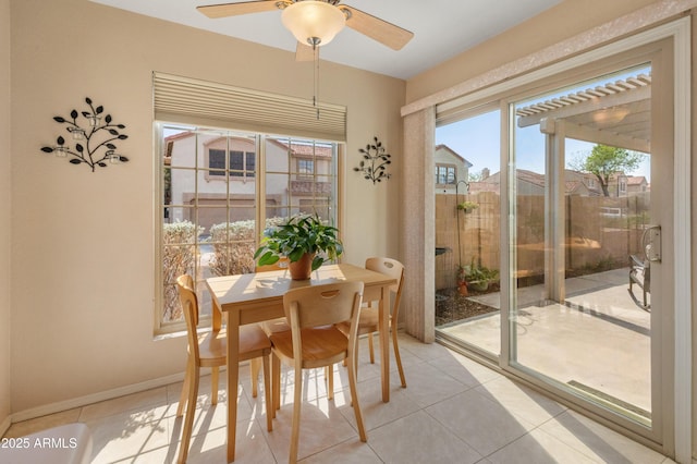 dining space featuring light tile patterned flooring, a ceiling fan, and baseboards