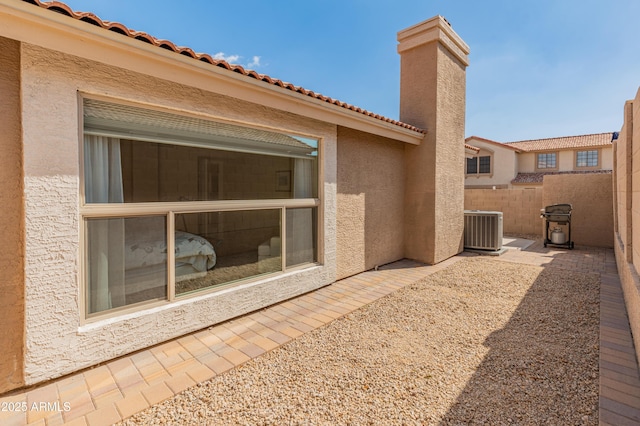 rear view of property with a patio, cooling unit, fence, a chimney, and stucco siding