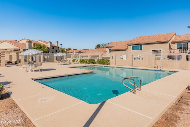 community pool with a residential view, a patio, and fence