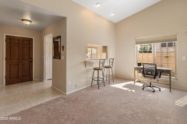 carpeted office space with tile patterned flooring, baseboards, and high vaulted ceiling